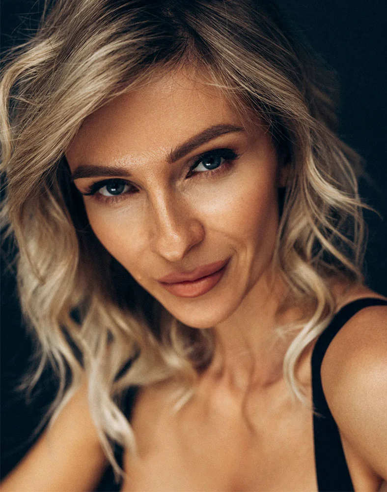A close up shot of a woman with short blonde curly hair glancing into the camera. - Brow Lift in Marina Del Rey, CA