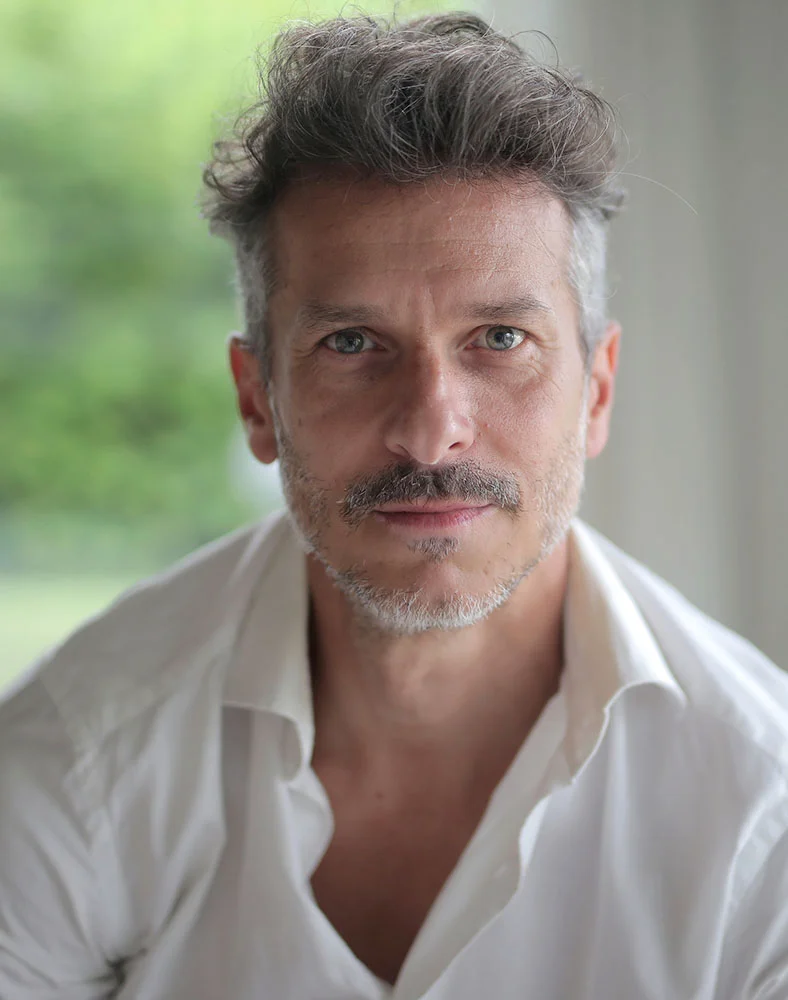 A close up shot of a man with grey facial hair and short hair, wearing a white button up. - Face Lift for Men in Marina Del Rey, CA